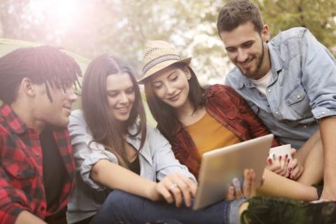 Four young adults looking at laptop