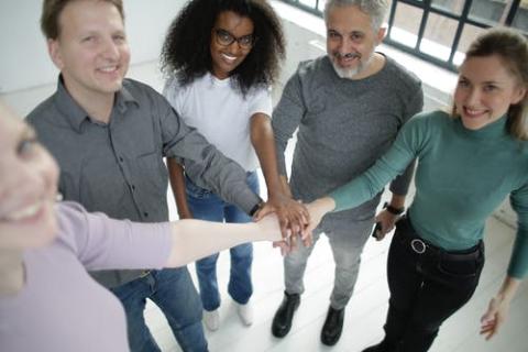 People from different backgrounds standing with hands together