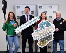 Minister with three sportspeople holding Volunteer in Sports signs